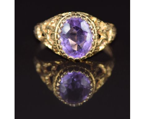 A 9ct gold ring set with an oval cut amethyst in a textured pierced setting, 2.6g, size P