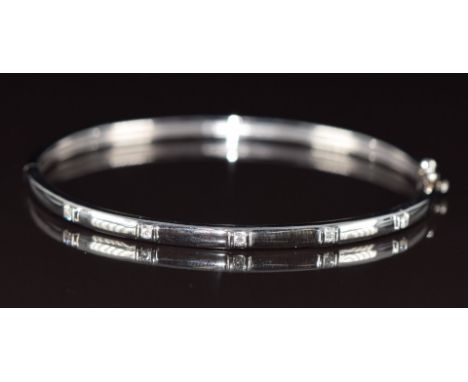 A 9ct white gold bangle set with five diamonds, 12g, 5.8 x 5.3cm