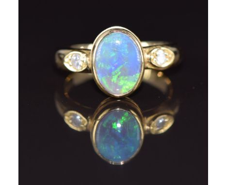 An 18ct gold ring set with an oval black opal cabochon and diamonds, 5.4g, size K