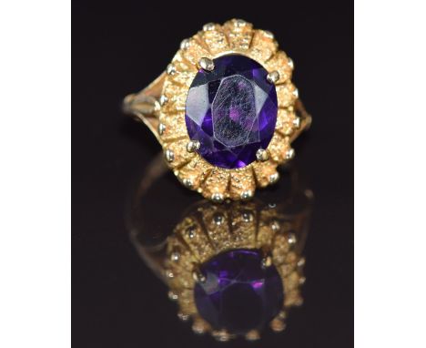 A 9ct gold ring set with an oval cut amethyst of approximately 3.9g&nbsp;with textured border, 7g, size N