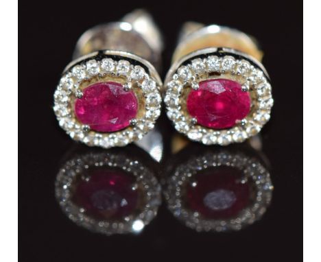 A pair of 18k white gold earrings each set with an oval cut ruby of approximately 0.3ct surrounded by white sapphires, 2g&nbs