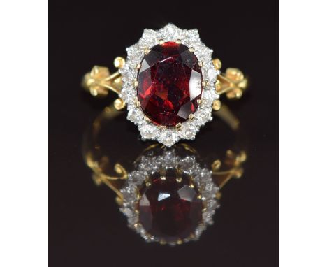 An 18ct gold ring set with an oval cut garnet of approximately 2.8ct surrounded by diamonds, 4.8g, size O