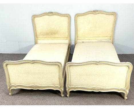 A pair of vintage French Louis XVI style single bedsteads, with moulded and craquelure cream painted ends and mattress divan 