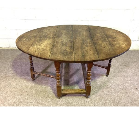 An oak gateleg table, early 18th century, English provincial, with a large planked plain oval drop leaf top, set on a base bo