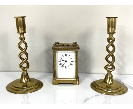A vintage brass cased carriage clock, unsigned enamel dial; also two twist stem brass candlesticks (3)