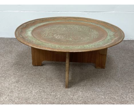 A very large vintage Islamic embossed copper tray, early 20th century, set on a typical stand, the tray decorated with lapete