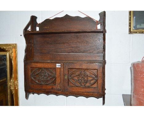 A CARVED OAK HANGING SHELF, with double cupboard doors