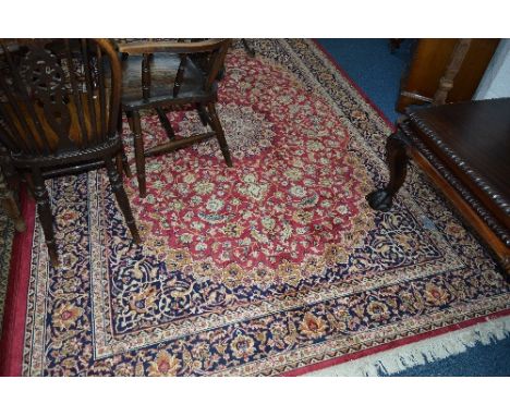 A LATE 20TH CENTURY MACHINE WOVEN SILK EFFECT CARPET SQUARE, claret and navy blue ground, foliate design, approximate size 28