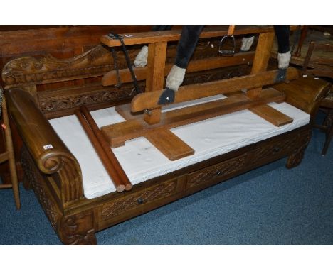 A LARGE CARVED HARDWOOD THREE SEATER BENCH, with scroll ended arms, three drawers and a removable cushion, approximate size w