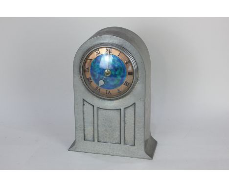 A Liberty &amp; Co English pewter mantle clock with circular turquoise enamel dial enclosed within arched case with hammered 