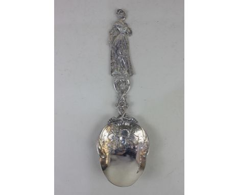 A large imported Victorian silver marriage spoon, the figural handle of a women holding a flower, with pierced floral scrolli