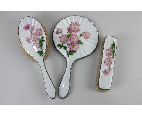 A George VI silver and enamel three-piece dressing table set of hand mirror, hair and clothes brush, with white enamel backs 