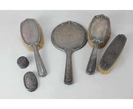An early 20th century silver dressing table set of three brushes, hand mirror, and bottle top, with engraved ribbon and hareb