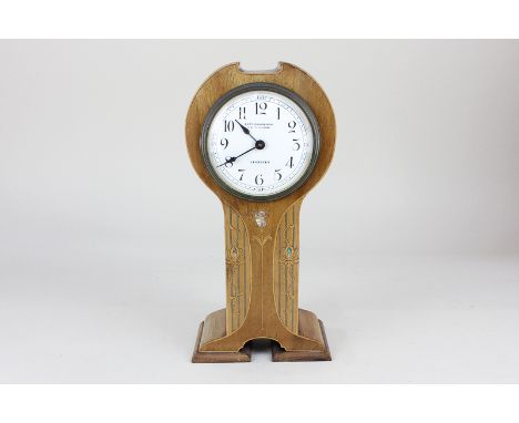 An Art Nouveau mantel clock in shaped case inlaid with sinuous plants, the white enamel dial with Arabic numerals, marked Cur