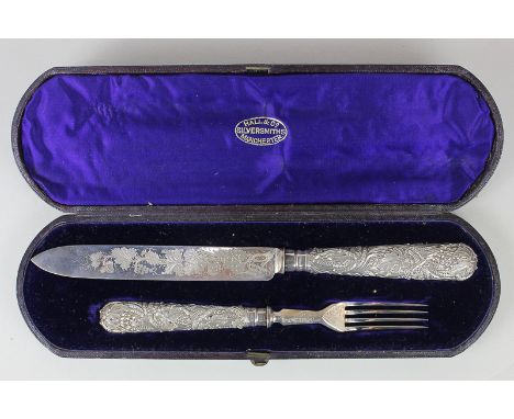 A Victorian cased silver serving set of knife and fork with engraved floral blade and handles cast in relief with vines and g