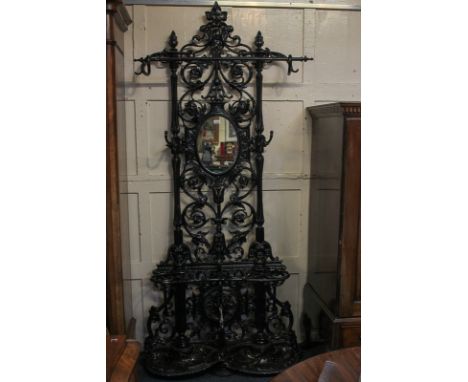 A Coalbrookdale type black painted cast iron hall stand with oval mirror, rail, four hooks, and two stick stands with shell-s