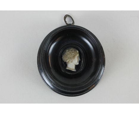 An oval miniature portrait profile on glass depicting the head of a woman in side profile, 3cm by 2.5cm