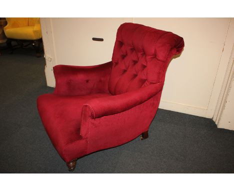 A Victorian red button upholstered armchair on turned front legs and castors