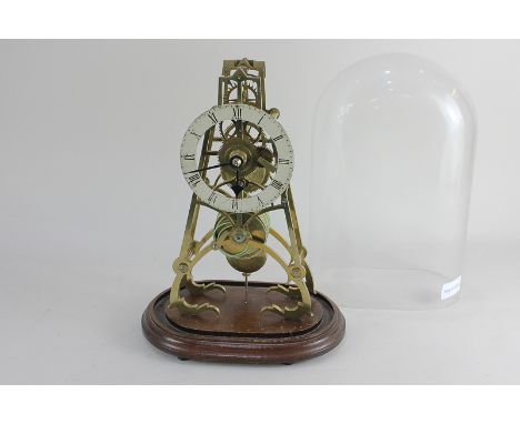 A brass skeleton clock with white enamel dial and Roman numerals, on oval wooden base under glass dome, 28cm high