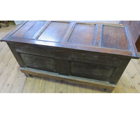 An 18th century oak coffer, having four panel rising lid and raised on stiled feet, width 52ins x depth 23.5ins x height 25in