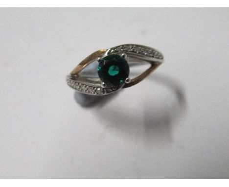 A single stone ring, the green stone set in a wishbone mount, with diamond style chips to one shoulder on each side, finger s