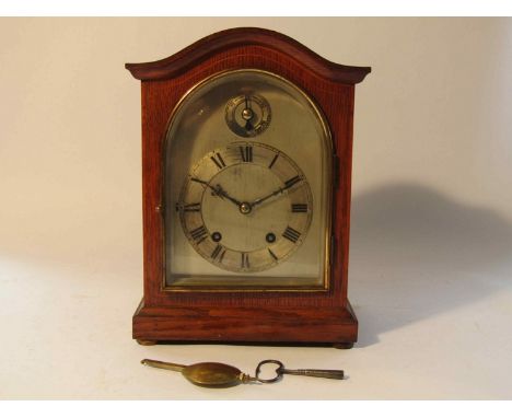 An early 20th Century oak mantel clock with silvered arched dial and Roman chapter ring and slow/fast subsidiary dial, Contin