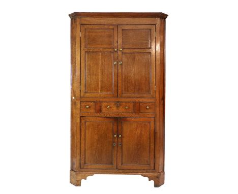 A George III Oak Free-Standing Corner Cupboard, circa 1800, the moulded cornice above double fielded panelled doors enclosing