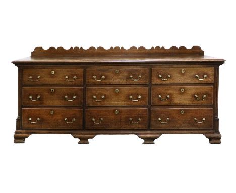 A George III Oak Enclosed Dresser Base, 3rd quarter 18th century, the shaped gallery above a boarded top with nine oak-lined 