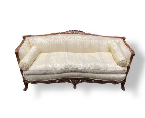 A 19th century Continental carved walnut three seat sofa, of crescent form with floral and flamed cresting, upholstered in iv