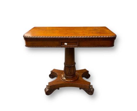 An early 19th century mahogany card table with gadrooned detail, the lotus carved pedestal set on quatreform platform base. G