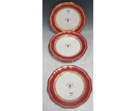 A set of six 19th century English porcelain armorial plates, the deep raspberry borders with gilded banding and rims. (6)Over