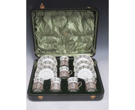 Cased set of coffee cans and saucers, the cans fitted with silver mounts by Walker and Hall Sheffield, the cups J C Crescent 
