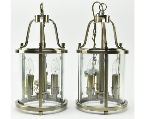 A matching pair of contemporary designer Hollywood Regency ceiling light pendants. Each of barrel form with clear glass panel