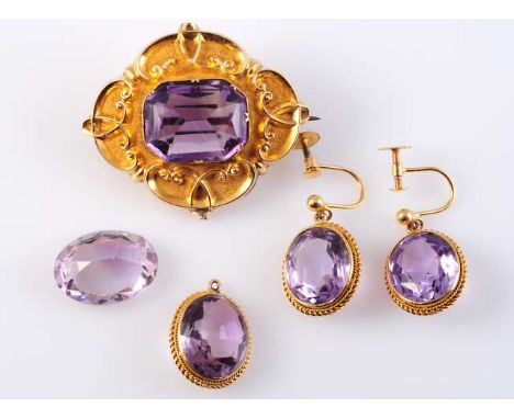 AN AMETHYST AND GILT-METAL BROOCH, the rectangular cut amethyst collet set to the centre of a symmetrical scroll work and tex