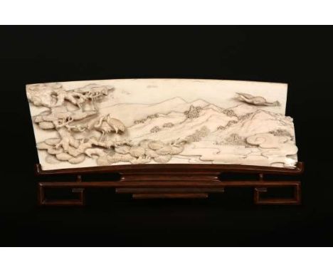 A CHINESE IVORY PANEL, 19th Century, carved in relief with cranes and boughs of prunus in a landscape, on a hardwood stand. I