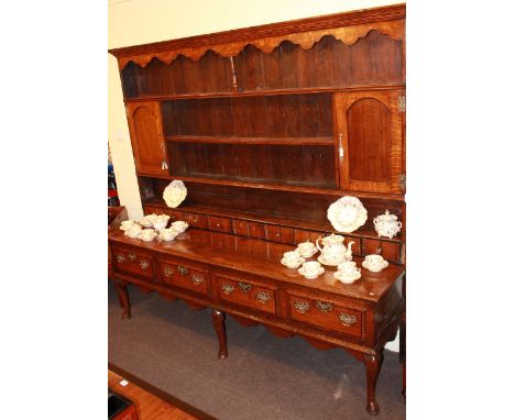 A GEORGE III OAK DRESSER AND RACK, of Shropshire type, the boarded rack with a pair of arched-panel door cupboards and spice 