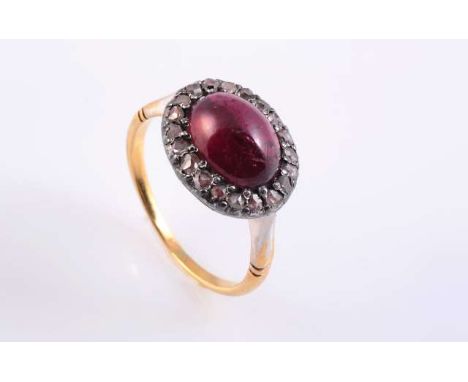 A GARNET AND DIAMOND RING, c.1870-80, the oval cabochon cut garnet claw set within a surround of twenty rose cut diamond high