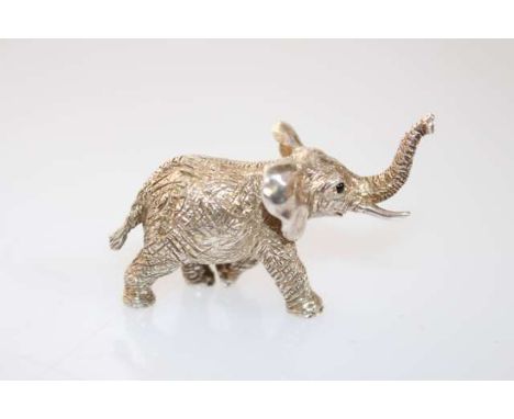 A SILVER MINIATURE MODEL OF AN ELEPHANT, London 1963, cast in a realistic pose with trunk up. 6cm 