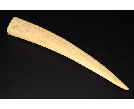 AN INUIT CARVED WALRUS TUSK, carved to one side with hunters preparing their boats, the reverse with hunters in a boat target