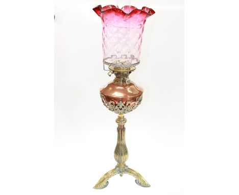 A 19TH CENTURY COPPER AND BRASS OIL LAMP, the tripod brass base issuing a bulbous stem below an openwork brass cup holding a 