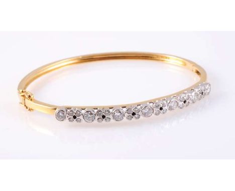 A DIAMOND SET BANGLE, the seven brilliant cut collet set diamonds alternately spaced with six mounts of four smaller brillian