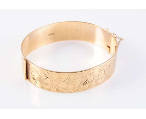 A 9 CARAT GOLD BANGLE, engraved with scrolling foliage, hallmarked. 30 grams