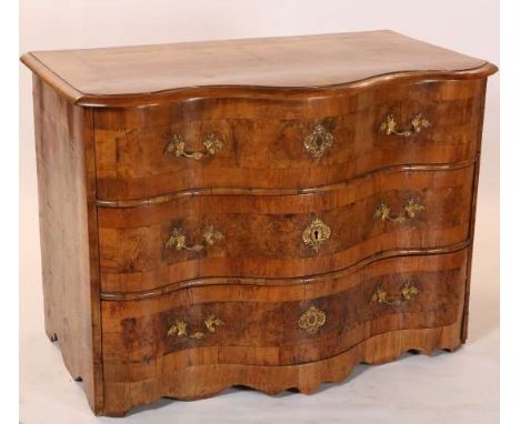 AN 18TH CENTURY WALNUT SERPENTINE COMMODE, PROBABLY SOUTH GERMAN, the top with broad crossbanding above three drawers fitted 