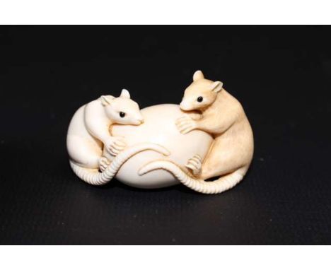 A JAPANESE IVORY NETSUKE OF TWO RATS CLUTCHING AN EGG, Meiji period (1868-1912), incised characters to an amber reserve. 5cm