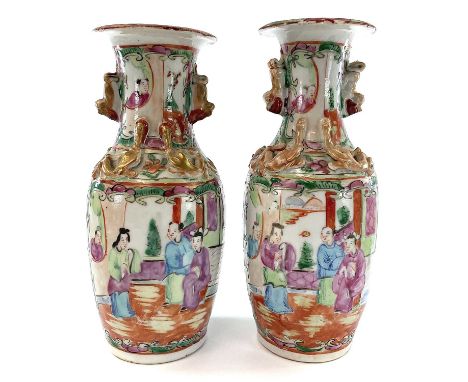 A pair of Chinese Canton porcelain vases, 19th century, each with a panel enclosing figures in an interior setting, opposed b