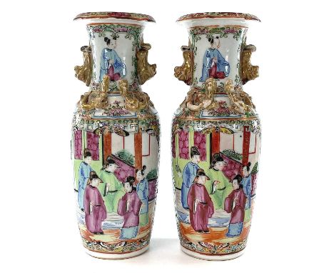 A pair of Chinese Canton porcelain vases, 19th century, each with a panel enclosing figures in an interior setting, opposed b