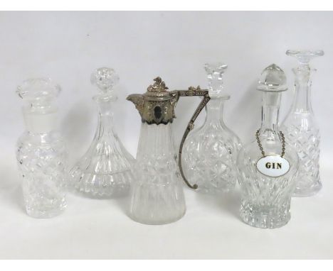 A cut glass claret jug with ornate silver plated handle, a decanter with an enameled gin label & four other glass decanters