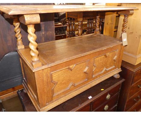 An early 20th century geometric light oak fold-over monks bench, having typical hinged box seat twin panelled base, on squat 