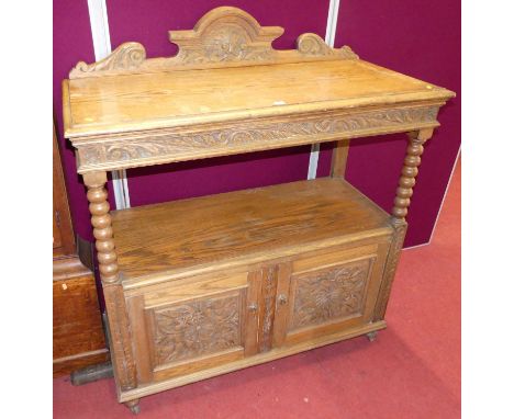An early 20th century floral relief carved oak ledge back two-tier buffet, having bobbin turned supports over twin relief car