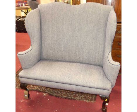 An early 20th century mahogany framed and later fabric upholstered twin hump back wing sofa, in the Georgian taste, raised on